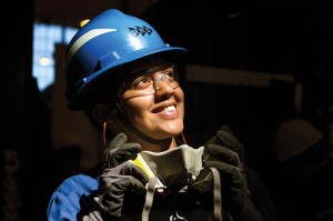 Colaboradora MRS olha para o alto e está usando equipamentos de proteção individual como capacete, óculos e luvas