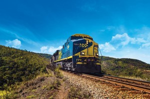 Locomotiva MRS em destaque, circulando em trecho cercado por vegetação rasteira