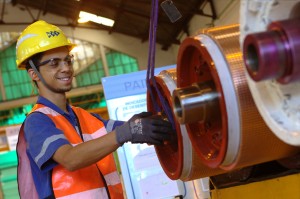 Colaborador usando equipamentos de proteção individual manuseia equipamento em ambiente de oficina